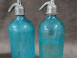 pair of blue glass soap dispensers with metal handles