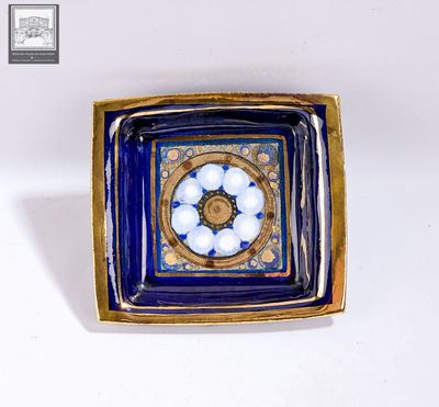 une photo d'une assiette bleue et dorée avec des boules blanches