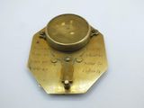 an antique brass compass on a white surface with writing on it