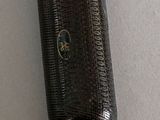 a brown glass bottle with a black handle on a white surface