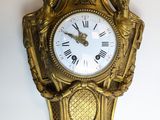 une horloge dorée accrochée au mur, avec des chiffres romains