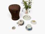 un vase contenant des fleurs, à côté d'autres vases et bols