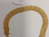 a close up of a gold chain bracelet on a white surface