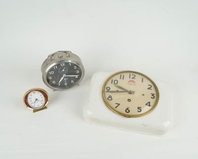 deux horloges et une montre posées sur une surface blanche