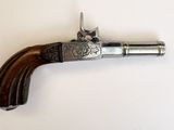 un vieux pistolet avec une poignée en bois sur une surface blanche