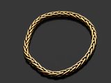 un bracelet en or avec un motif tressé sur fond noir