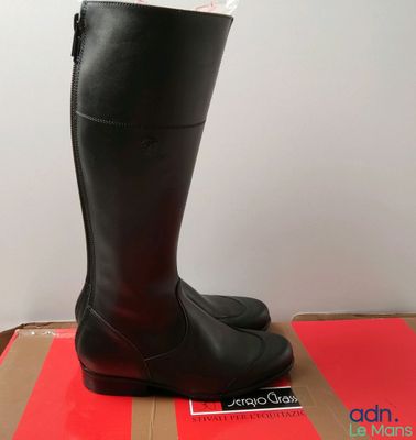des bottes en cuir noir avec des fermetures éclair sur le dessus d'une boîte rouge