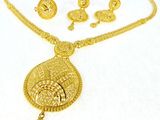 a close up of a gold necklace and earrings on a white surface