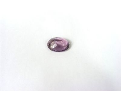 une pierre ovale violette posée sur une surface blanche, avec un fond blanc