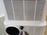 a white air conditioner sitting on the floor in a room