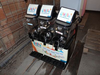 trois distributeurs de sodas posés sur une table en bois