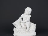 a white figurine of a boy sitting on a rock