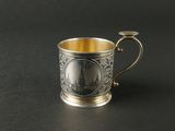 une coupe en argent munie d'une anse, posée sur une surface noire