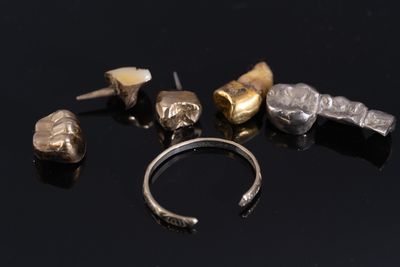 five different pieces of silver and gold on a black surface