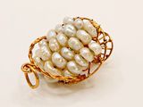 gold plated wire basket of white pearls on a white background