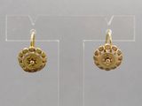 deux paires de boucles d'oreilles en or exposées dans une vitrine transparente