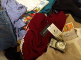 a pile of clothes and a camera on a bed