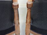 two wooden chairs with black cushions on them