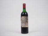 une vieille bouteille de vin posée sur une surface blanche