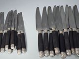 huit couteaux sont alignés en rang sur une table