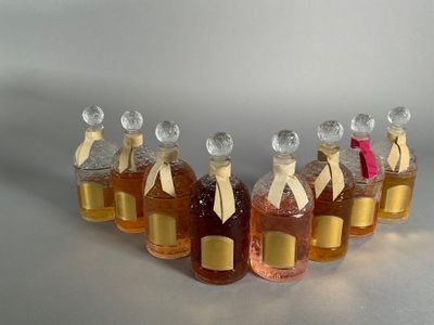 six bottles of honey sit in a row on a white surface