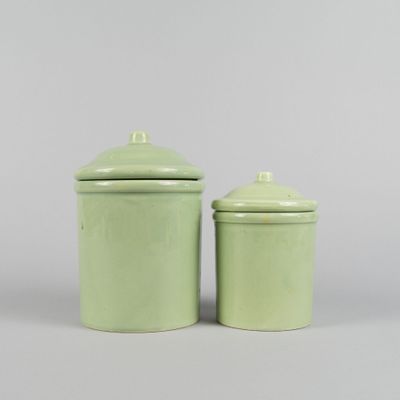 pair of green ceramic canisters with lids on a gray background
