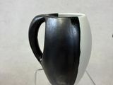 a black and white cup sitting on a clear stand