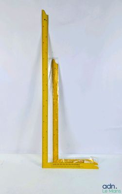 une règle jaune sur fond blanc, à côté d'un mur blanc