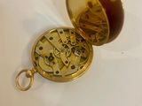 a gold colored pocket watch with a brown face