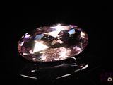 a close up of a pink diamond on a black surface