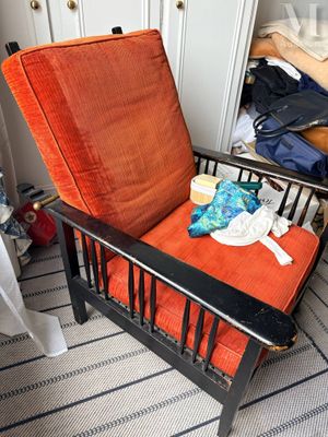 une chaise avec un coussin orange dans un coin de la pièce