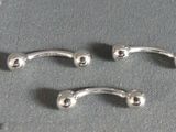 two silver metal nose piercings on a gray surface