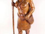 wooden statue of a woman holding a stick and a basket