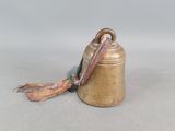 a bell that is sitting on the ground with a scarf around it