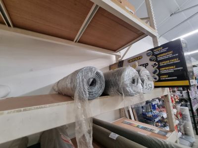 deux rouleaux de tissu posés sur une étagère dans un magasin