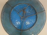 a blue plate with a wire around it on the wall