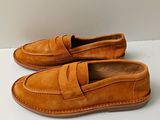 Mocassins pour homme de couleur beige posés sur une surface blanche, sur fond blanc