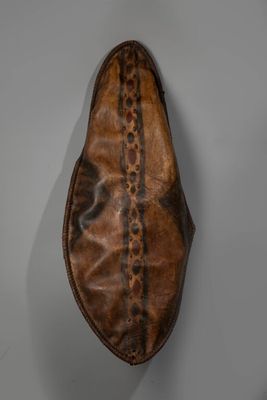 un gros plan d'une chaussure en cuir marron posée sur une surface blanche