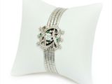 an image of a diamond and emerald bracelet on a white pillow
