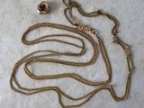 gros plan d'un collier en or avec une chaîne sur une surface blanche