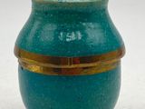 a blue vase with a gold rim sitting on a white surface