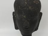 statue of the head of a buddha on a black stand
