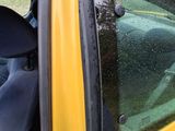 a dog sitting in the driver ' s seat of a yellow car