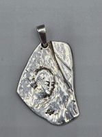 Pendentif en argent représentant un visage féminin, complet avec sa bé