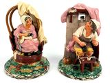 pair of ceramic figurines of a woman and a man sitting in a chair