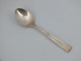 a silver spoon on a white plate on a table