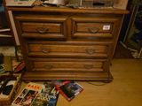 une commode en bois avec des magazines posés par terre à côté