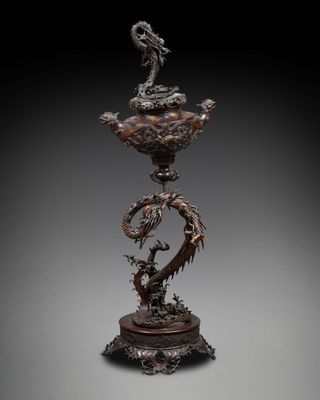 a bronze vase with two birds on top of it