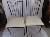 pair of black metal chairs with cream seat cushions