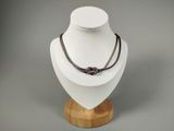 collier avec un nœud sur un support en bois, sur fond gris